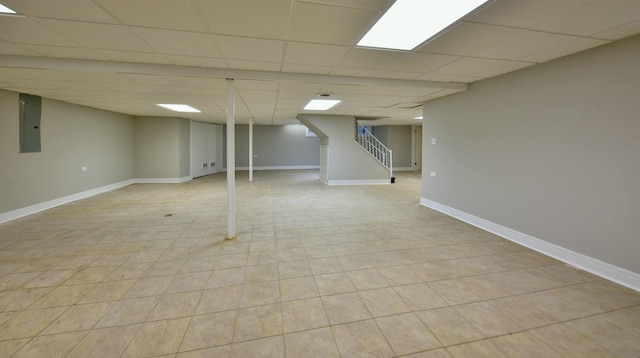 basement with light tile floors and a paneled ceiling