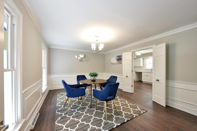 dining area with ornamental molding, dark wood-type flooring, and an inviting chandelier