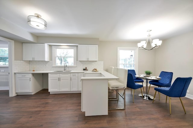 kitchen with pendant lighting, plenty of natural light, white cabinets, and dark wood-type flooring