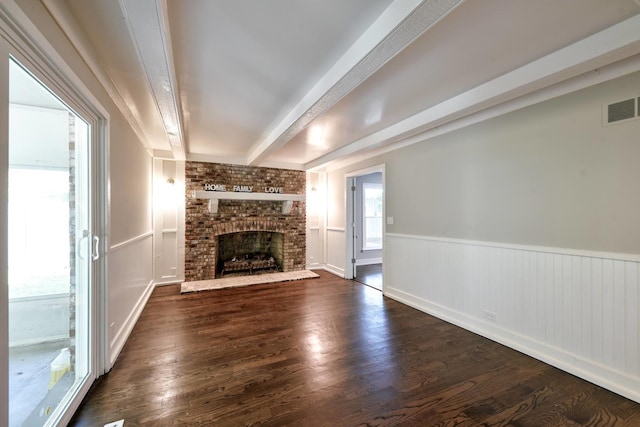 unfurnished living room featuring a fireplace, brick wall, dark hardwood / wood-style floors, and beam ceiling