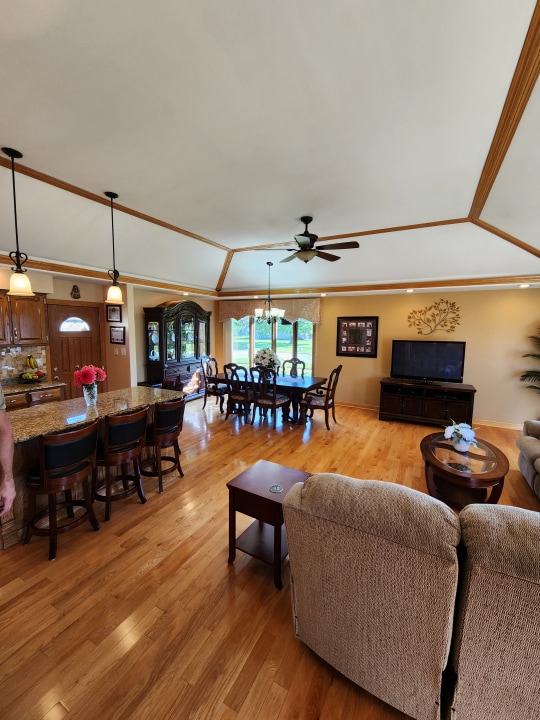 living room with light hardwood / wood-style floors, lofted ceiling, and ceiling fan with notable chandelier