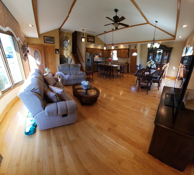 living room with vaulted ceiling, light wood-type flooring, and ceiling fan with notable chandelier