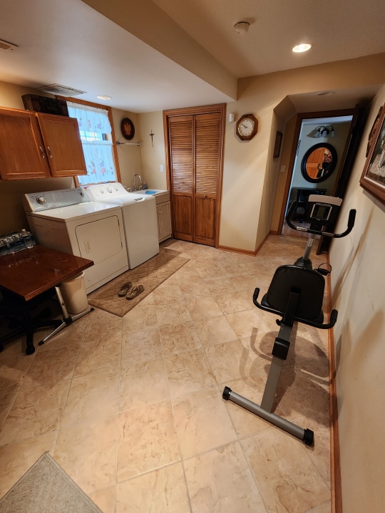 exercise area featuring light tile floors, separate washer and dryer, and sink