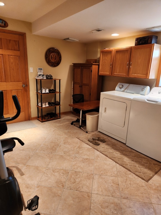 laundry area with light tile flooring, cabinets, and independent washer and dryer