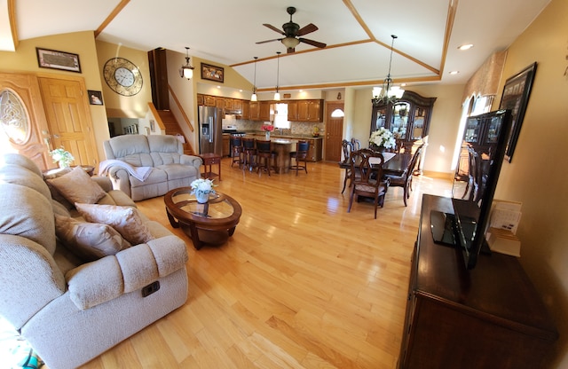 living room with high vaulted ceiling, light hardwood / wood-style flooring, and ceiling fan with notable chandelier