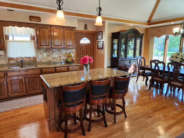 kitchen featuring light wood-type flooring, a breakfast bar area, decorative light fixtures, sink, and a chandelier