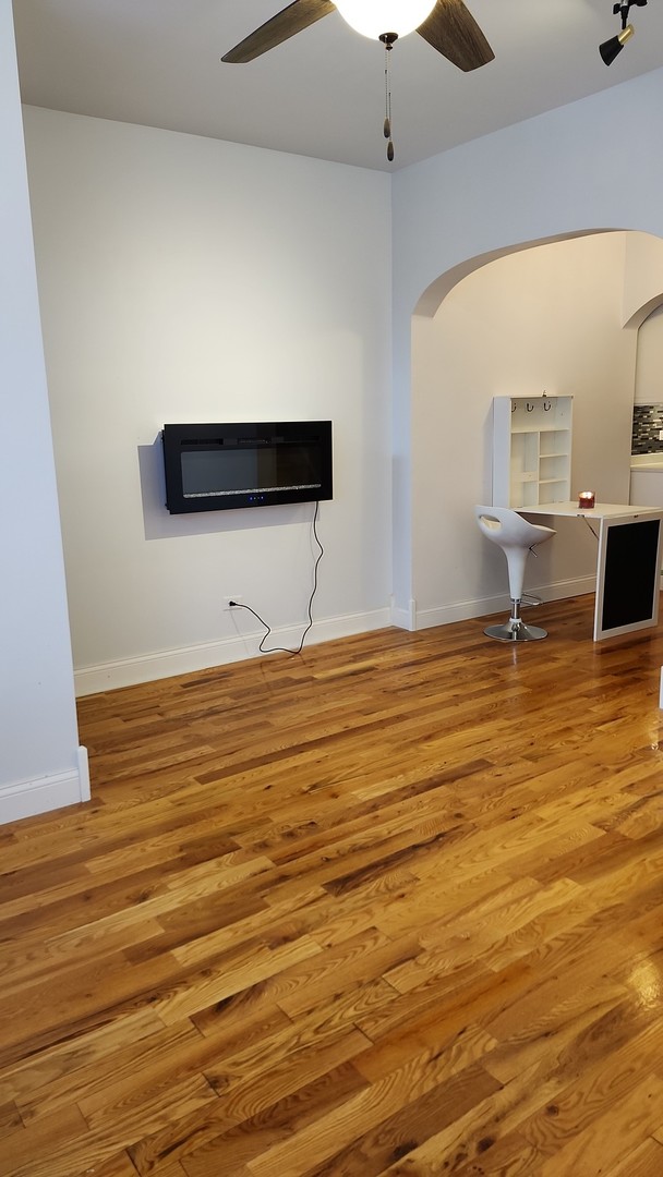 unfurnished living room featuring ceiling fan and wood-type flooring