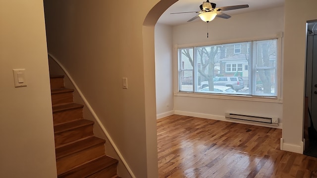 stairway with light hardwood / wood-style floors, a healthy amount of sunlight, ceiling fan, and baseboard heating