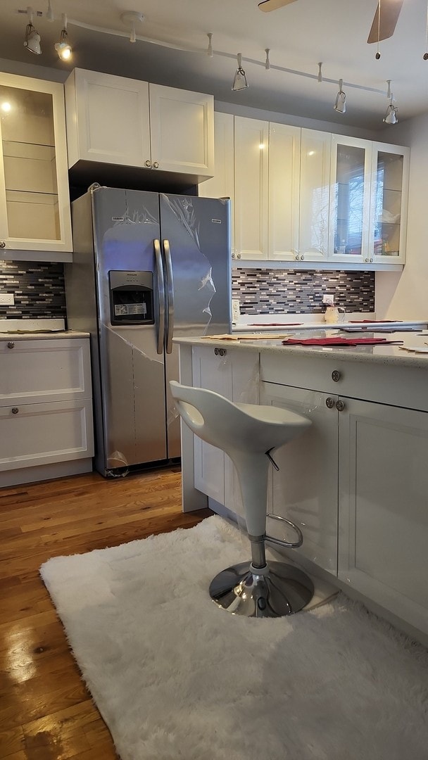 kitchen featuring white cabinetry, dark hardwood / wood-style floors, ceiling fan, stainless steel refrigerator with ice dispenser, and tasteful backsplash