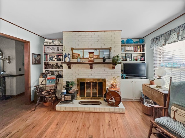 living room with a brick fireplace, hardwood / wood-style flooring, and crown molding