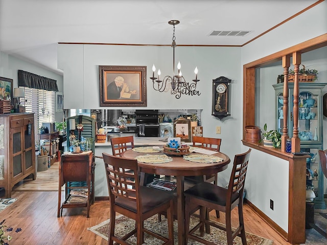 dining area featuring an inviting chandelier, light hardwood / wood-style flooring, and ornamental molding