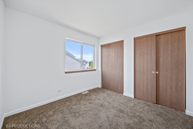 unfurnished bedroom with carpet and two closets