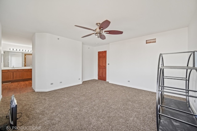 unfurnished bedroom featuring connected bathroom, carpet, sink, and ceiling fan