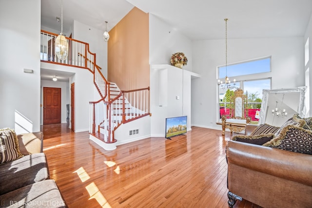 living room featuring hardwood / wood-style flooring, high vaulted ceiling, and an inviting chandelier