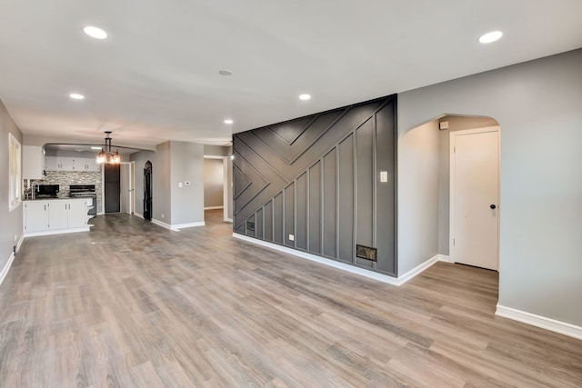 unfurnished living room featuring light wood-type flooring and a stone fireplace