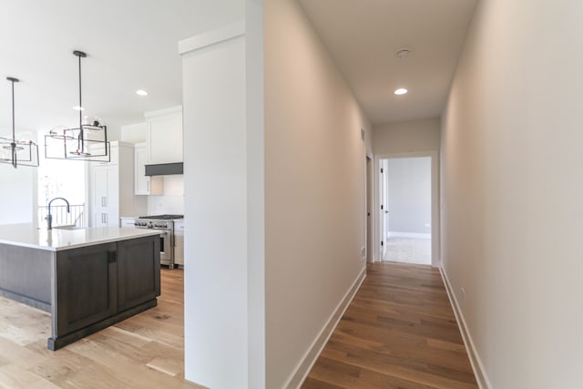 hall featuring a chandelier, sink, and light hardwood / wood-style flooring