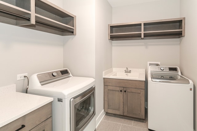 laundry area featuring washing machine and clothes dryer, sink, cabinets, and light tile floors