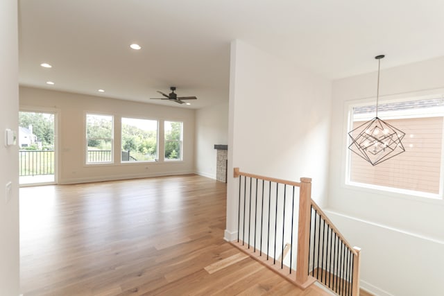 interior space with light hardwood / wood-style floors and ceiling fan with notable chandelier