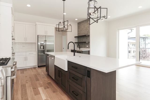 kitchen with light hardwood / wood-style floors, a notable chandelier, tasteful backsplash, white cabinets, and sink