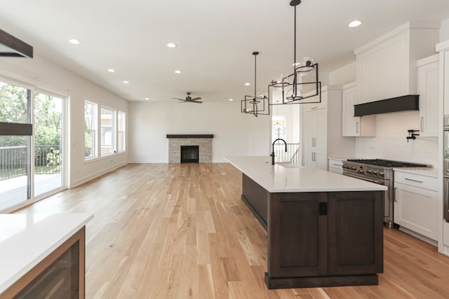 kitchen with light hardwood / wood-style floors, a fireplace, white cabinetry, and ceiling fan with notable chandelier