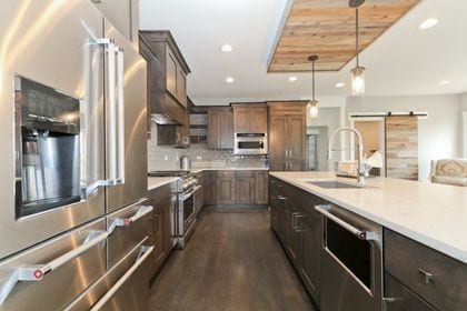 kitchen with a barn door, sink, dark hardwood / wood-style floors, appliances with stainless steel finishes, and decorative light fixtures