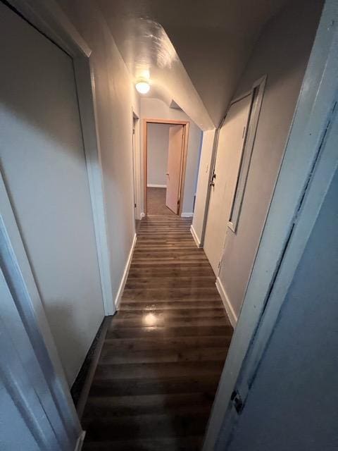 corridor with dark wood-type flooring and vaulted ceiling