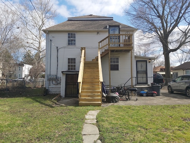 rear view of property featuring a patio area, a wooden deck, and a lawn