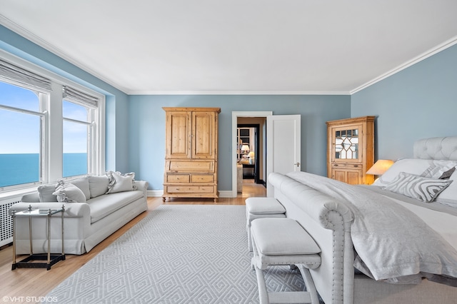 bedroom featuring a water view, light wood-type flooring, and ornamental molding