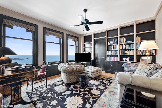 living room featuring ceiling fan, a water view, plenty of natural light, and hardwood / wood-style flooring