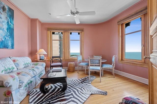 living room featuring light hardwood / wood-style floors, ornamental molding, and ceiling fan