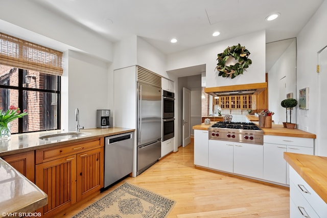 kitchen featuring sink, appliances with stainless steel finishes, white cabinets, butcher block counters, and light wood-type flooring