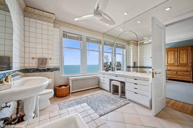 bathroom featuring toilet, ceiling fan, radiator heating unit, tile walls, and tile flooring