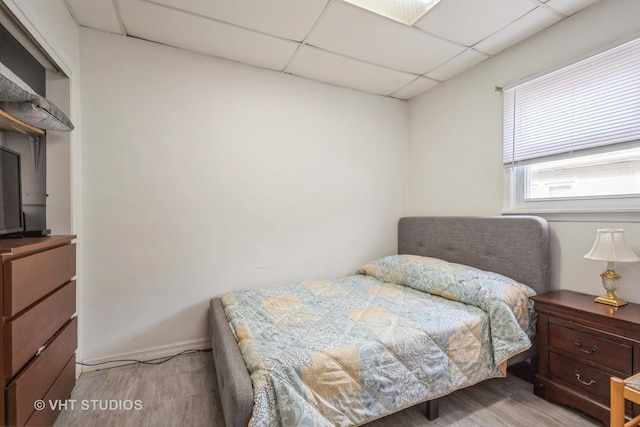 bedroom featuring a paneled ceiling and light wood-type flooring