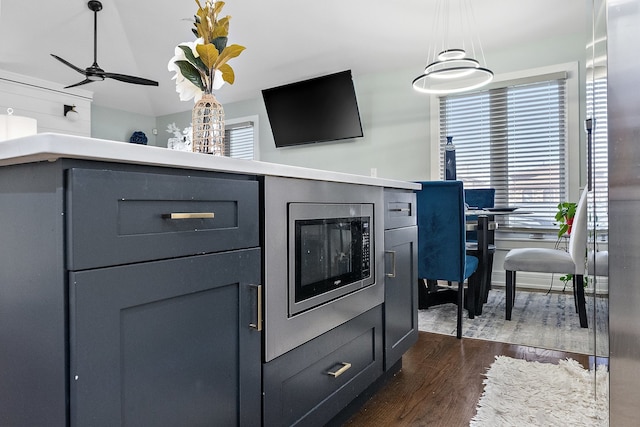 interior details featuring dark wood-type flooring, stainless steel microwave, and ceiling fan