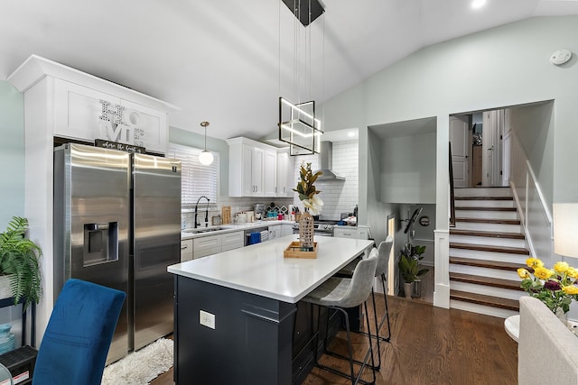 kitchen with pendant lighting, vaulted ceiling, stainless steel fridge, backsplash, and dark hardwood / wood-style floors