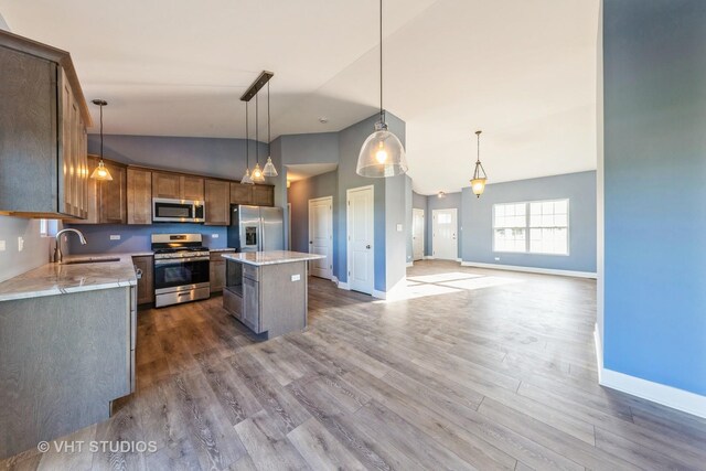 kitchen featuring stainless steel appliances, decorative light fixtures, dark hardwood / wood-style floors, and a center island