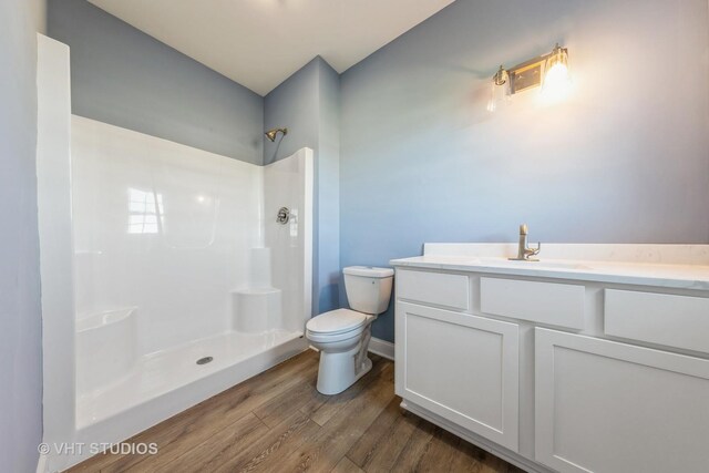 bathroom with toilet, a shower, vanity, and hardwood / wood-style floors