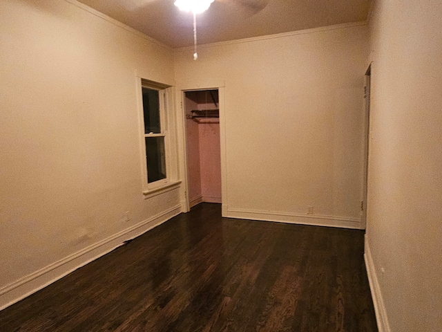 empty room featuring ornamental molding, a ceiling fan, baseboards, and dark wood-style floors