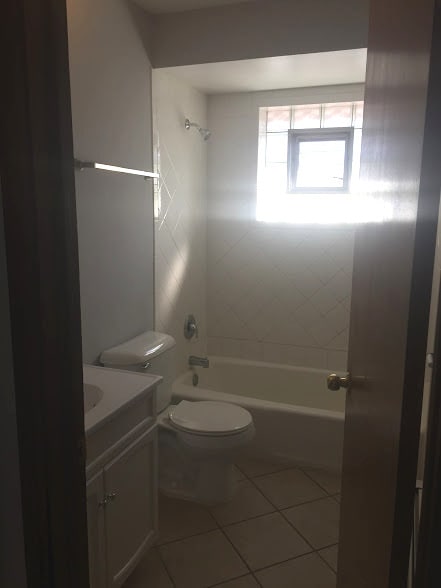 full bathroom featuring tiled shower / bath combo, toilet, vanity, and tile flooring