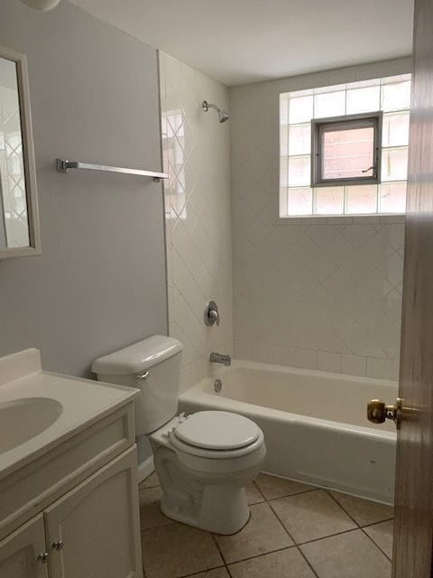 full bathroom with tile flooring, tiled shower / bath, toilet, and vanity