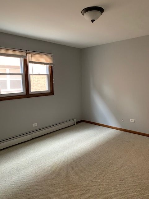 carpeted spare room featuring baseboard heating