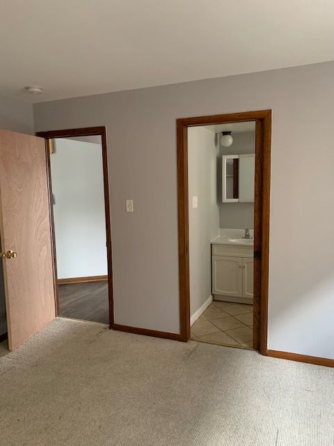 unfurnished bedroom with connected bathroom, light colored carpet, and sink