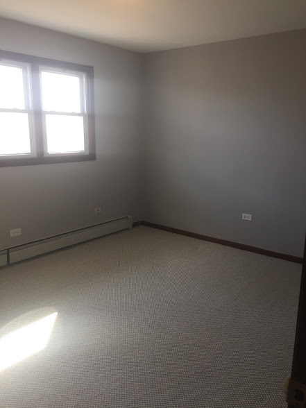 carpeted spare room featuring a baseboard radiator