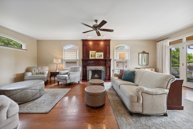 living room featuring ceiling fan, dark hardwood / wood-style floors, a large fireplace, and plenty of natural light