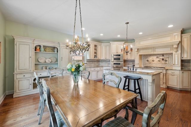 dining room with an inviting chandelier, light hardwood / wood-style floors, and sink