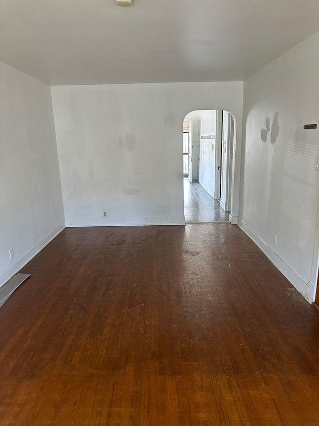 unfurnished room featuring wood-type flooring and arched walkways