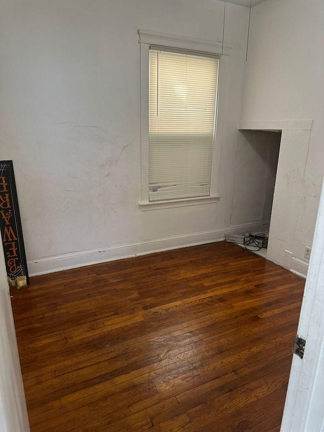 spare room with baseboards and hardwood / wood-style floors