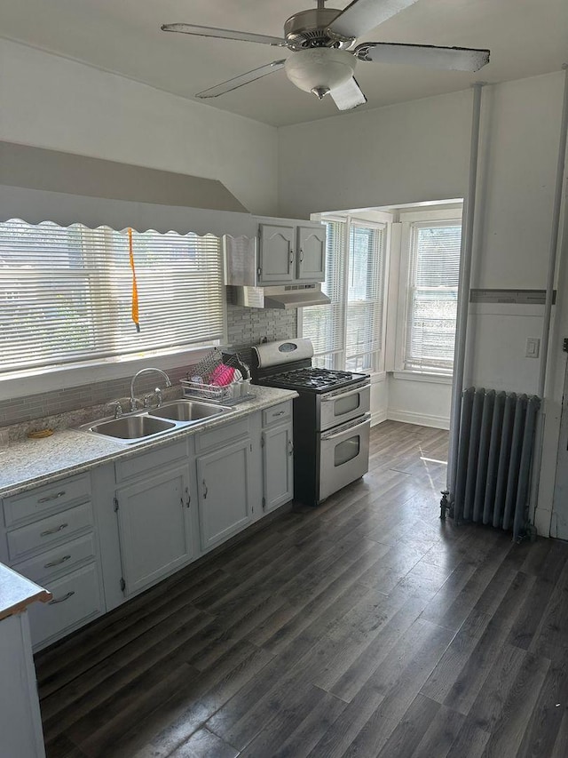 kitchen with dark wood-style floors, radiator, a sink, and double oven range