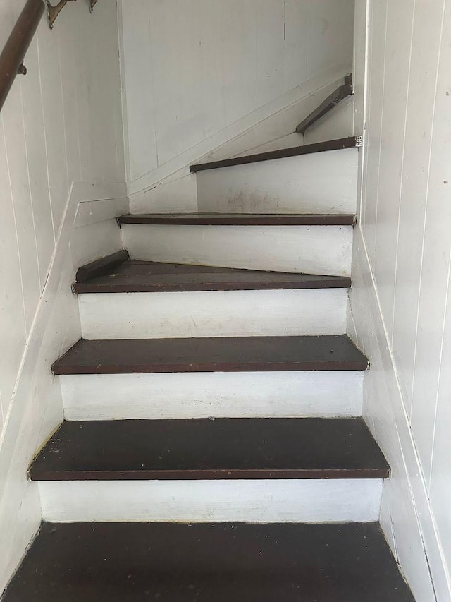 staircase featuring wooden walls