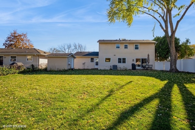 rear view of property with a yard and central AC unit